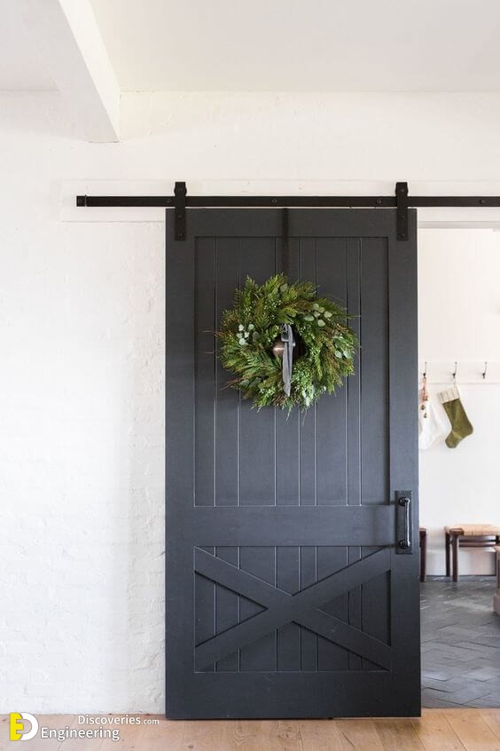 a-grey-sliding-barn-door-with-handles-with-a-large-greenery-wreath-brings-a-cheer-holiday-feel.jpg