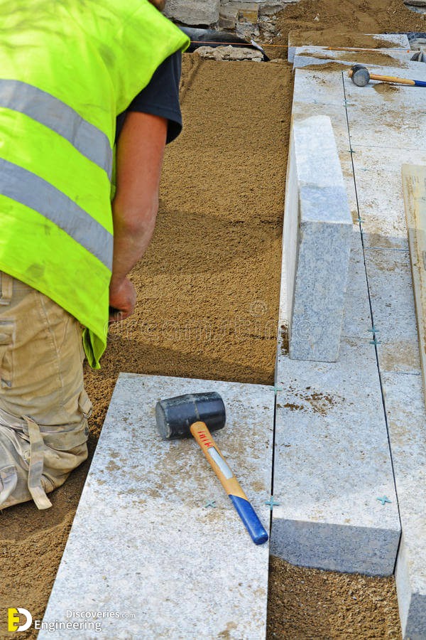 worker-creating-screeding-sand-bedding-to-level-laying-granite-paver-blocks-permeable-paving-installation-series-54394532.jpg